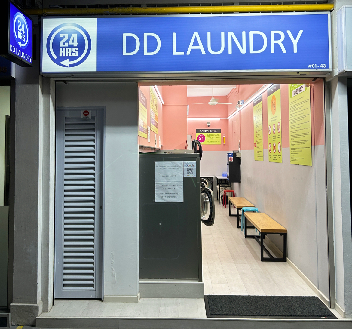 DD Laundry shopfront at night with blue signboard, 24 hours roundel and pink interior