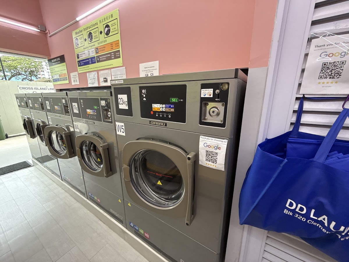 Row of Girbau industrial washers with DD Laundry tote bags hanging