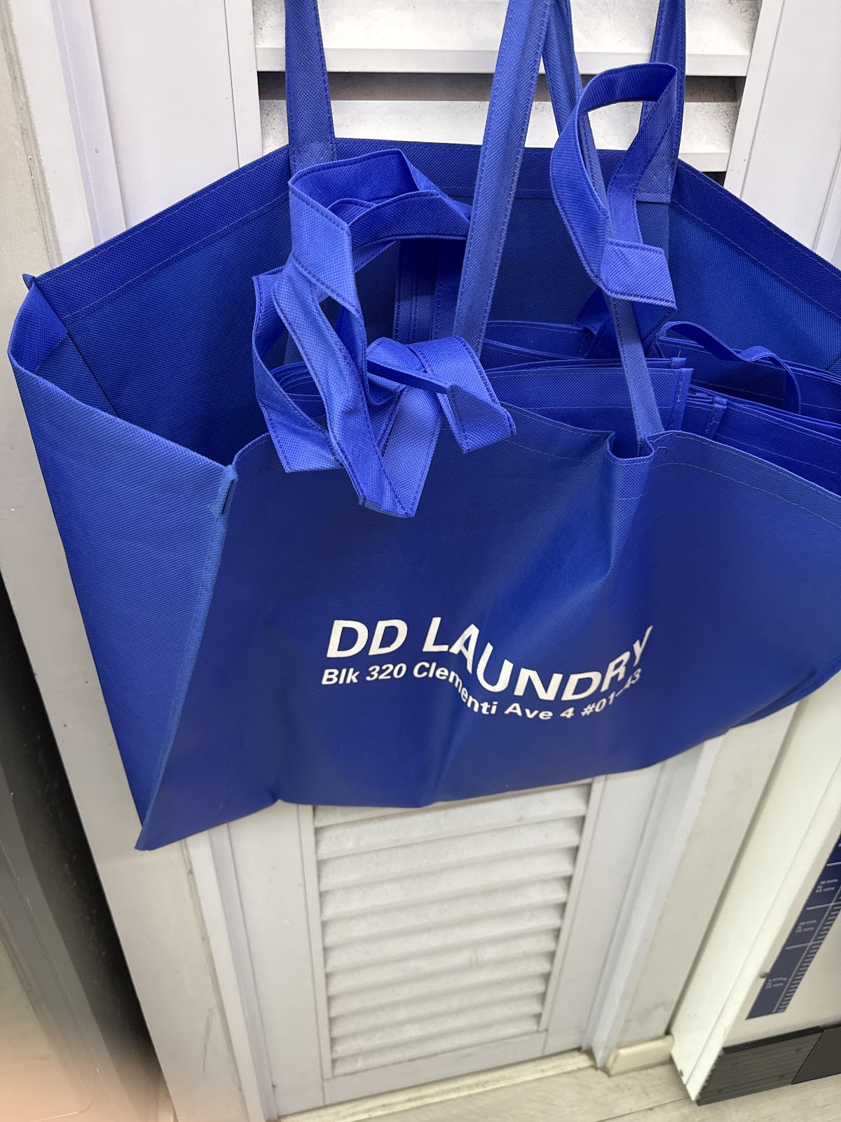 DD Laundry branded blue tote bags with the shop address printed